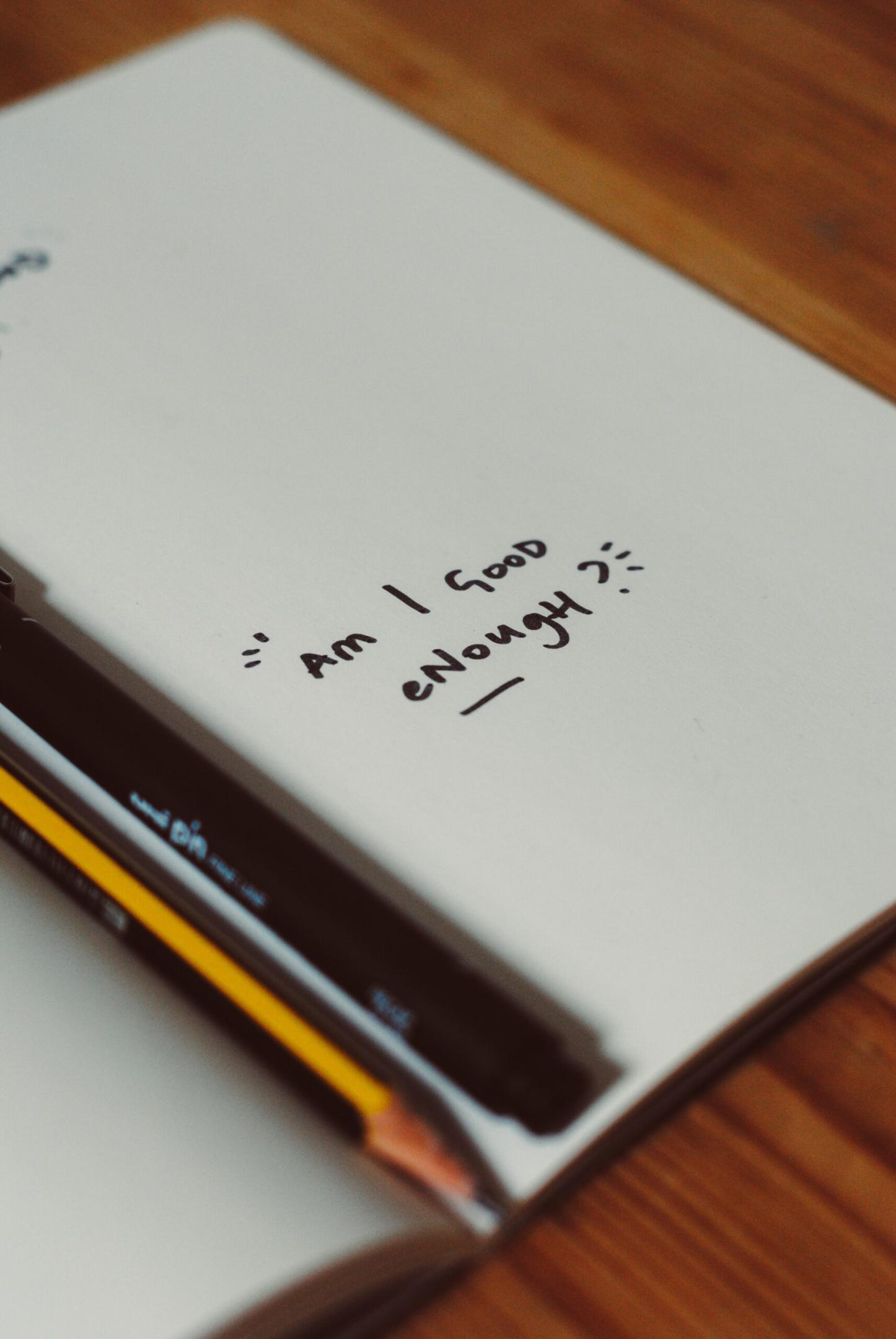 Writing on paper asking Am I Good Enough